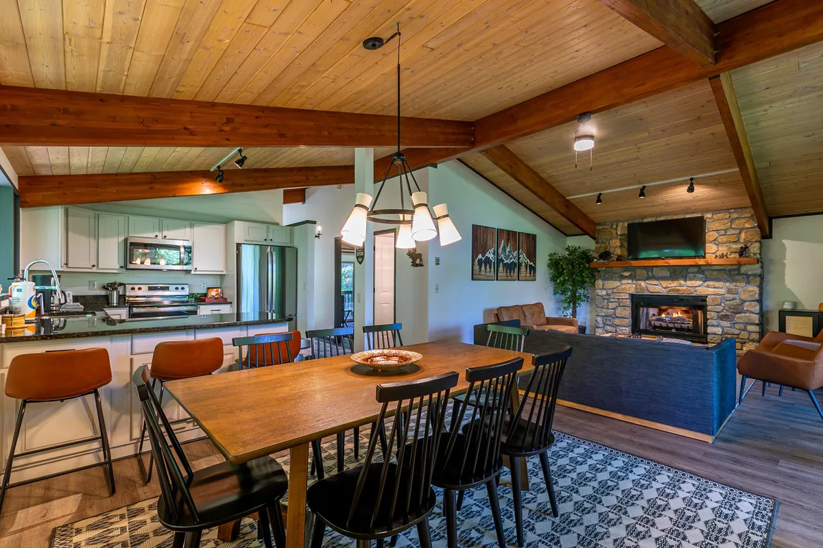 An inviting dining area seamlessly connected to the kitchen, featuring a large dining table, warm fireplace, and artistic touches on the wall. The space is designed for family meals and social gatherings, with plenty of room for everyone to relax and share stories.