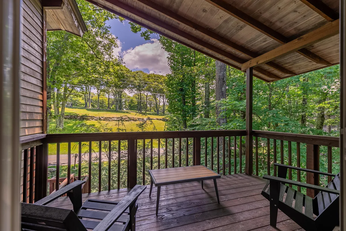 A peaceful wooden deck surrounded by trees, offering outdoor furniture and a sweeping open landscape view. The inviting setting suggests relaxation, social gatherings, and observing wildlife—ideal for family downtime after active days.